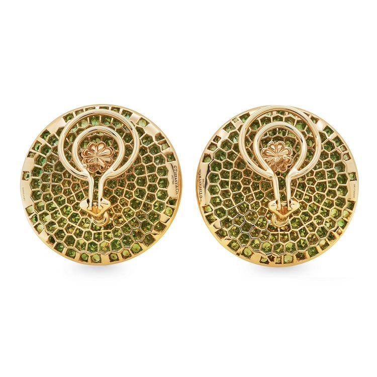 Side profile of a Tiffany & Co. Feathered Cloak gold stud earring, highlighting the three-dimensional layered design with emerald green tsavorite gemstones.