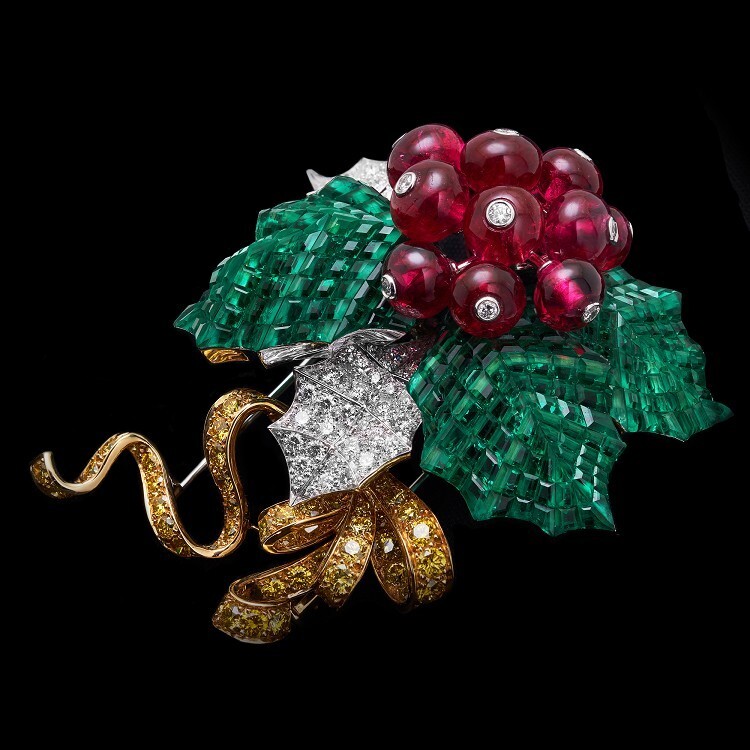 Detailed shot of the Van Cleef & Arpels Houx Mystérieux brooch, emphasizing the 'Secret Mosaic' emerald setting and brilliant yellow diamond ribbon.