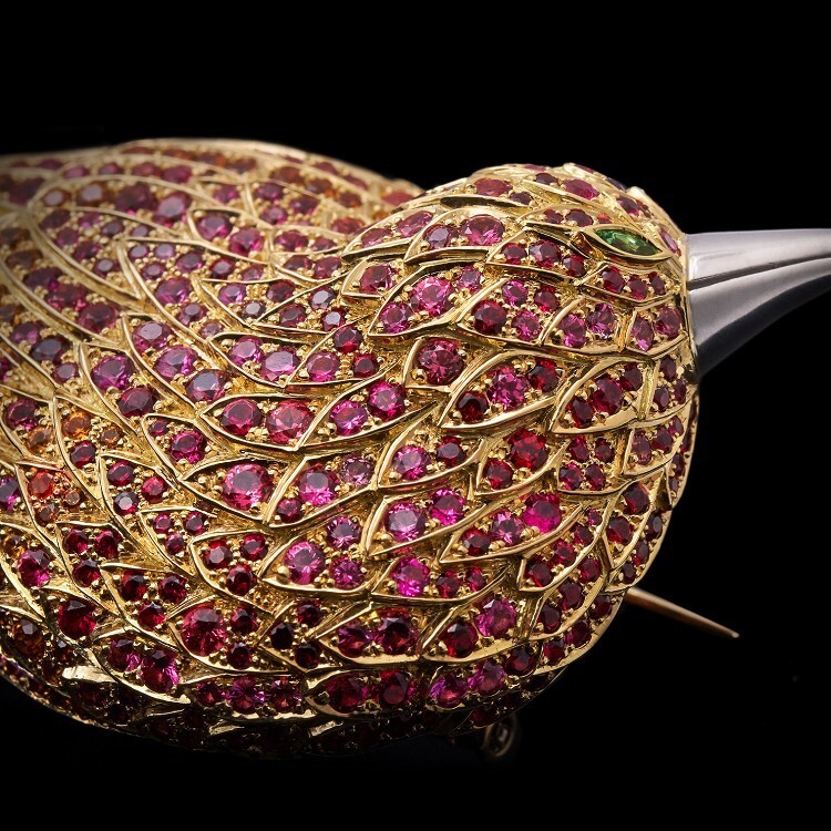 Detailed shot of the Tiffany Feathered Cloak brooch's tail feathers, featuring alternating red spinel, spessartite garnet, and shimmering diamond tips.