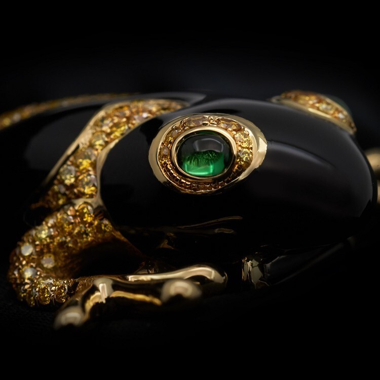 Three-quarter view of the Tiffany & Co. tree frog brooch, emphasizing its dynamic 'climbing' posture and brilliant gemstone accents.
