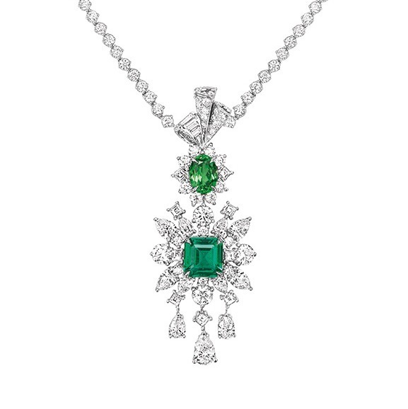 Close-up view of the Dior Soie Dior Plumetis Diamant Jaune necklace, showcasing its central emerald and tsavorite gemstones, diamond settings, and elegant ribbon motif.
