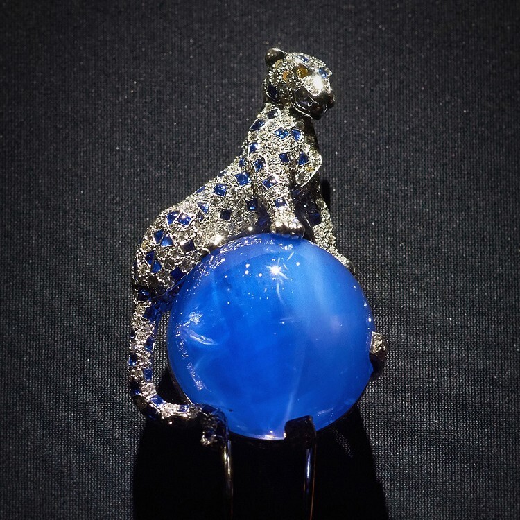 Full view of the Cartier Duchess of Windsor Panther Brooch, featuring its prominent 152.35-carat Kashmir sapphire clutched by the cheetah, against a dark background
